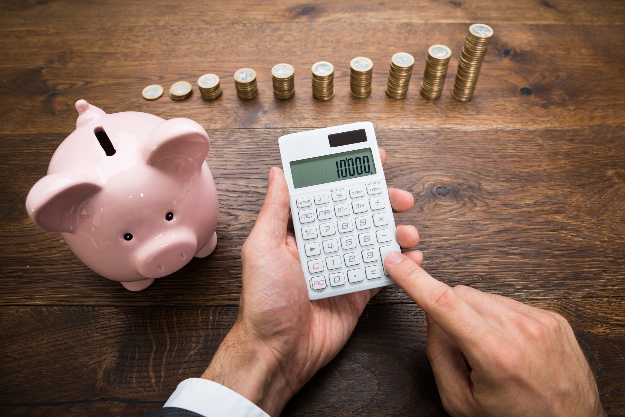 Businessman With Coins And Piggybank Using Calculator